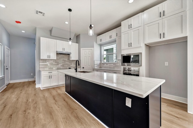 16362 Eastchase St, Montgomery, TX 77316 - kitchen with stainless steel appliances, under cabinet range hood, white cabinets, tasteful backsplash, and recessed lighting