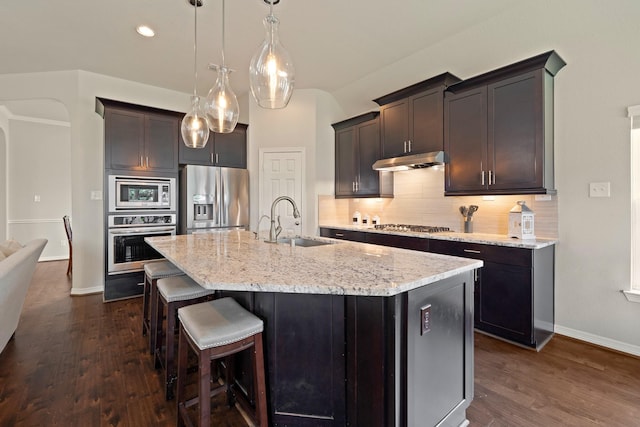 3426 Satton Ranch Ln, Fulshear, TX 77441 - kitchen featuring appliances with stainless steel finishes, under cabinet range hood, tasteful backsplash, dark wood finished floors, and recessed lighting