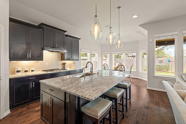 3426 Satton Ranch Ln, Fulshear, TX 77441 - kitchen with under cabinet range hood, light stone countertops, backsplash, a kitchen breakfast bar, and recessed lighting