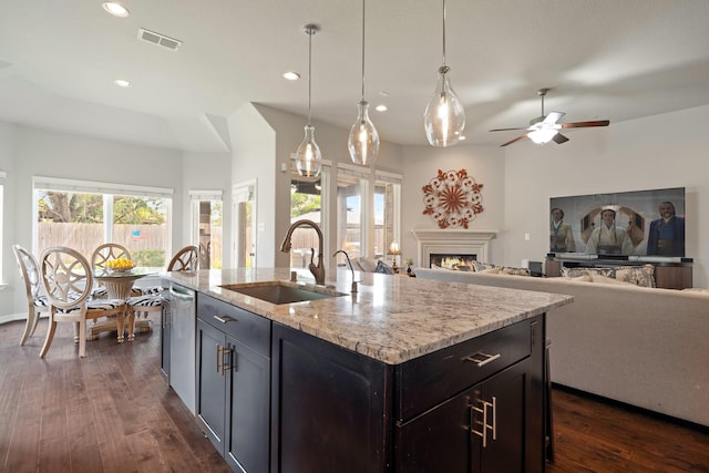 3426 Satton Ranch Ln, Fulshear, TX 77441 - kitchen with a ceiling fan, dark wood finished floors, a warm lit fireplace, light stone counters, and recessed lighting