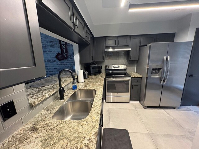 3244 Poe Dr, Montgomery, TX 77356 - kitchen featuring appliances with stainless steel finishes, under cabinet range hood, backsplash, light stone countertops, and light tile patterned flooring