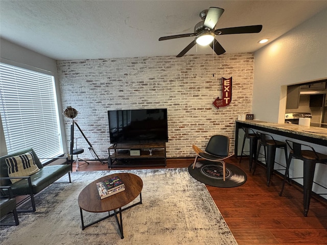 3244 Poe Dr, Montgomery, TX 77356 - living room with wood finished floors, a ceiling fan, healthy amount of natural light, and brick wall