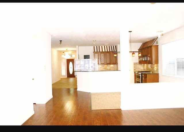 20518 Bonds Creek Ln, Spring, TX 77388 - kitchen with brown cabinetry, gas stove, wood finished floors, and decorative backsplash