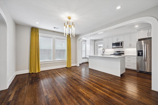 5001 Farmer St, Houston, TX 77020 - kitchen with appliances with stainless steel finishes, arched walkways, a kitchen island with sink, light countertops, and white cabinetry
