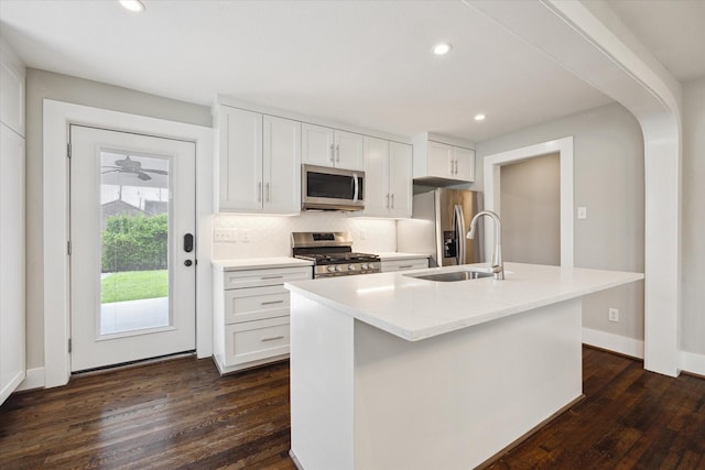5001 Farmer St, Houston, TX 77020 - kitchen featuring stainless steel appliances, dark wood-type flooring, white cabinets, a center island with sink, and tasteful backsplash