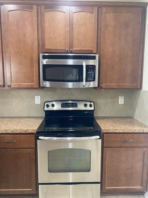 16707 Libson Falls Dr, Houston, TX 77095 - kitchen featuring stainless steel appliances, tasteful backsplash, and light stone counters