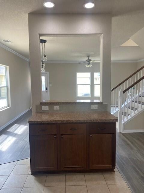 16707 Libson Falls Dr, Houston, TX 77095 - kitchen featuring crown molding, a ceiling fan, dark stone counters, light tile patterned floors, and dark brown cabinets