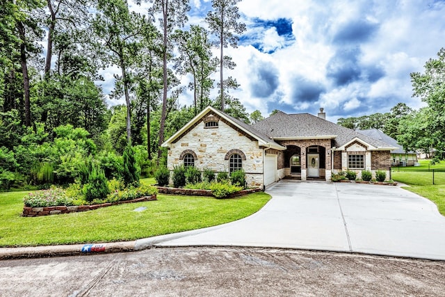 104 Drexal Dr, Huntsville, TX 77340 - french country style house with a garage, concrete driveway, stone siding, and a front yard