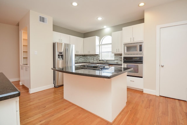9703 Riddlewood Ln, Houston, TX 77025 - kitchen featuring appliances with stainless steel finishes, light wood-type flooring, white cabinetry, decorative backsplash, and recessed lighting