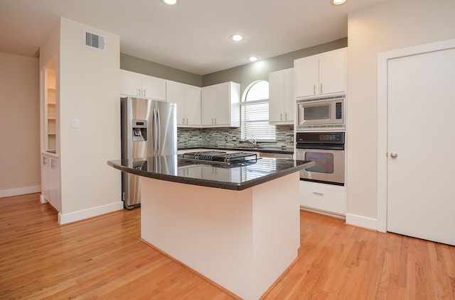 9703 Riddlewood Ln, Houston, TX 77025 - kitchen with appliances with stainless steel finishes, light wood finished floors, a kitchen island, white cabinetry, and recessed lighting