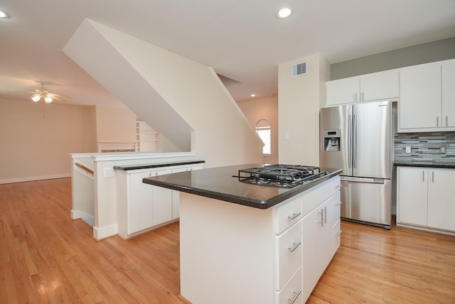 9703 Riddlewood Ln, Houston, TX 77025 - kitchen featuring stainless steel appliances, a kitchen island, light wood-style floors, dark countertops, and recessed lighting