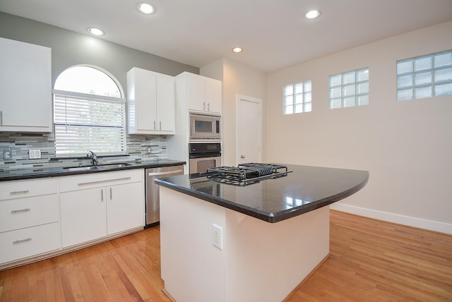 9703 Riddlewood Ln, Houston, TX 77025 - kitchen featuring stainless steel appliances, a center island, tasteful backsplash, light wood-style flooring, and recessed lighting
