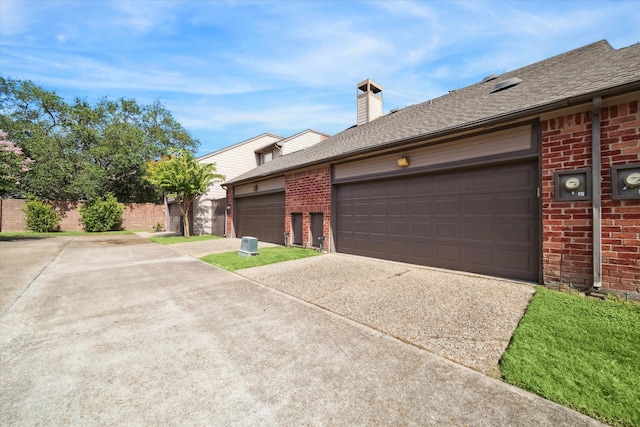 7447 Cambridge St Unit 15, Houston, TX 77054 - view of property exterior with brick siding, driveway, an attached garage, a chimney, and roof with shingles