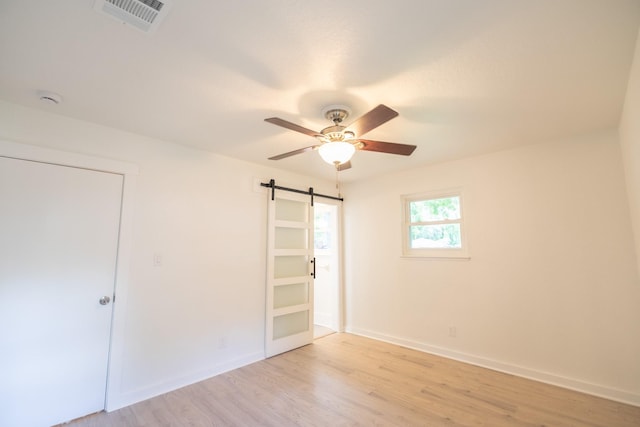 1025 Hathaway Ln, Marque, TX 77568 - unfurnished bedroom featuring a barn door, light wood finished floors, and ceiling fan