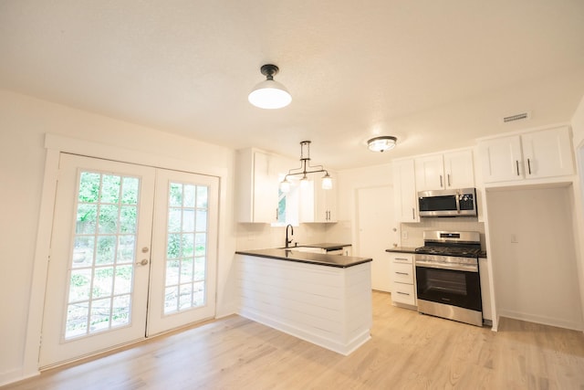 1025 Hathaway Ln, Marque, TX 77568 - kitchen with appliances with stainless steel finishes, dark countertops, light wood-style floors, and tasteful backsplash