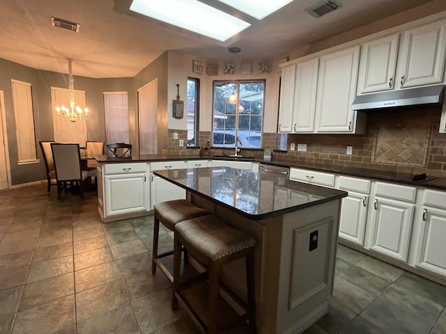 7922 Scenic Canyon Ln W, Houston, TX 77095 - kitchen with under cabinet range hood, black electric stovetop, a chandelier, tasteful backsplash, and white cabinets