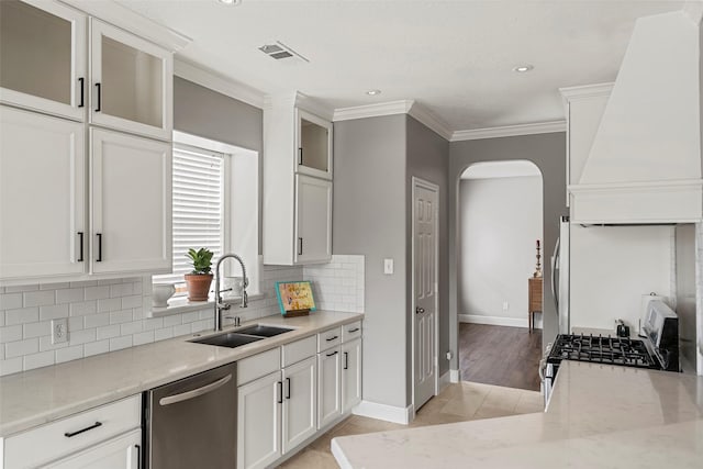23826 Spring Dane Dr, Spring, TX 77373 - kitchen with stainless steel appliances, ornamental molding, custom exhaust hood, arched walkways, and light stone counters