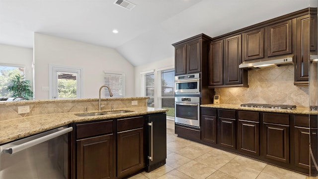 15314 Icet Creek Ave, Mont Belvieu, TX 77523 - kitchen with appliances with stainless steel finishes, vaulted ceiling, under cabinet range hood, tasteful backsplash, and light tile patterned floors