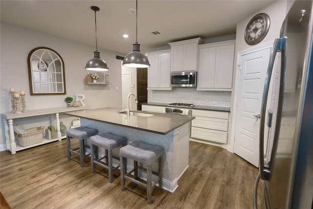 20503 Montecrest Cir, Spring, TX 77379 - kitchen with stainless steel appliances, dark wood finished floors, backsplash, white cabinetry, and a kitchen breakfast bar