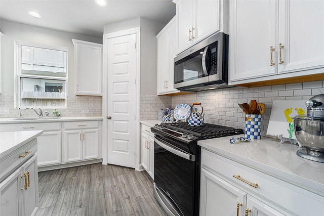 4101 Split Ivy Dr, Houston, TX 77080 - kitchen with stainless steel appliances, light countertops, white cabinets, light wood-style flooring, and decorative backsplash