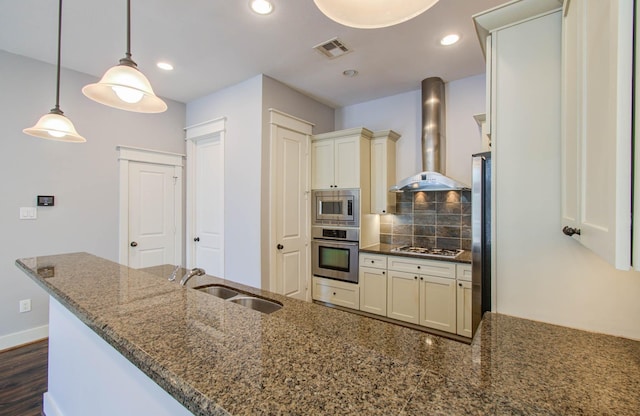 517 Fowler St, Houston, TX 77007 - kitchen featuring appliances with stainless steel finishes, wall chimney exhaust hood, decorative backsplash, dark stone counters, and decorative light fixtures