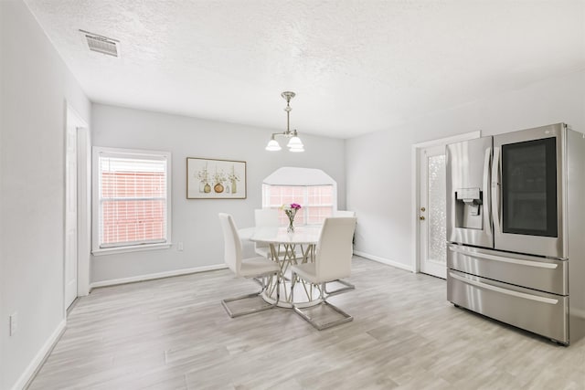 10329 Fairfax St, Houston, TX 77029 - dining area with a textured ceiling, light wood-style flooring, and a chandelier