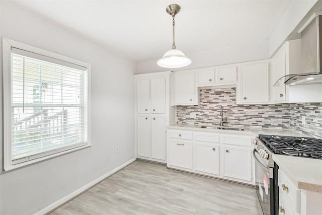 10329 Fairfax St, Houston, TX 77029 - kitchen featuring stainless steel range with gas cooktop, wall chimney exhaust hood, light countertops, tasteful backsplash, and white cabinets