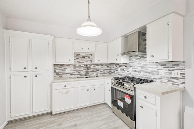 10329 Fairfax St, Houston, TX 77029 - kitchen with stainless steel range with gas stovetop, wall chimney range hood, light countertops, and white cabinetry