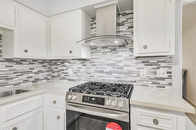 10329 Fairfax St, Houston, TX 77029 - kitchen with stainless steel range with gas stovetop, wall chimney range hood, tasteful backsplash, and white cabinetry