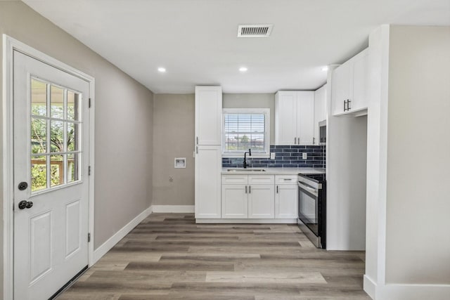 1000 W Thomas Ave, Pasadena, TX 77506 - kitchen featuring electric range oven, white cabinetry, recessed lighting, tasteful backsplash, and light wood finished floors