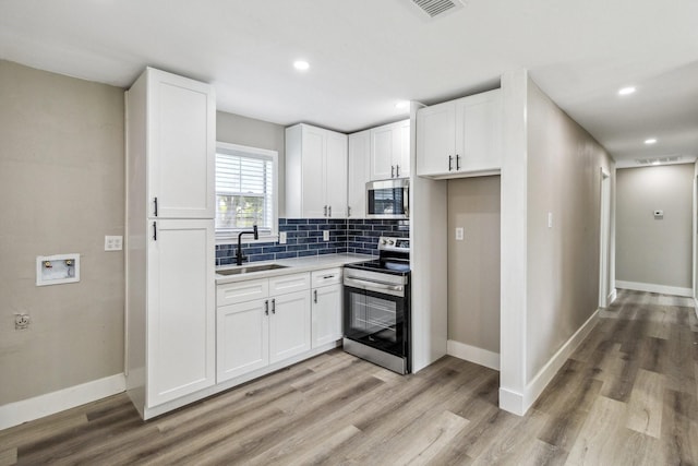 1000 W Thomas Ave, Pasadena, TX 77506 - kitchen with appliances with stainless steel finishes, light wood finished floors, white cabinetry, and recessed lighting