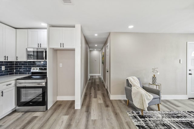 1000 W Thomas Ave, Pasadena, TX 77506 - kitchen with stainless steel appliances, light wood finished floors, white cabinets, tasteful backsplash, and light countertops