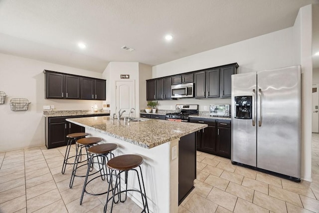 9618 Paloma Creek Dr, Tomball, TX 77375 - kitchen with appliances with stainless steel finishes, light stone countertops, a kitchen bar, a center island with sink, and light tile patterned floors
