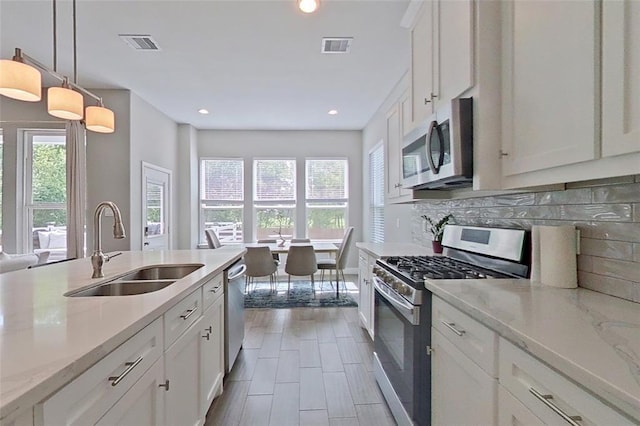 10747 Dulcimer St, Houston, TX 77051 - kitchen featuring stainless steel appliances, backsplash, white cabinetry, recessed lighting, and pendant lighting
