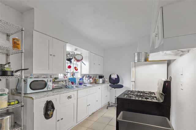 4115 Trail Lake Dr, Houston, TX 77045 - kitchen featuring white microwave, fridge, white cabinets, light countertops, and black gas stove