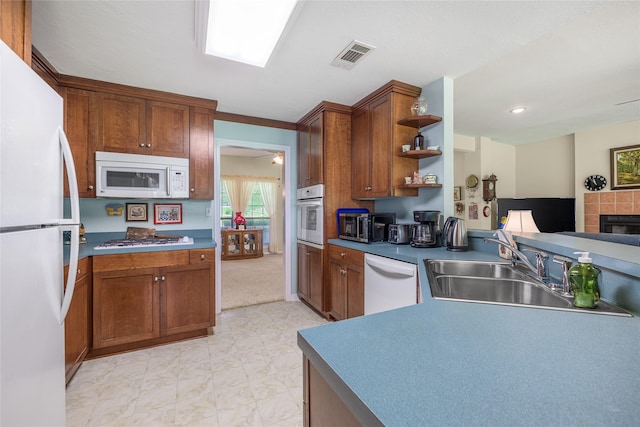 7027 Kurt Dr, Brenham, TX 77833 - kitchen with white appliances, open shelves, brown cabinetry, a tiled fireplace, and a ceiling fan