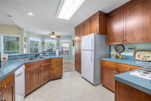 7027 Kurt Dr, Brenham, TX 77833 - kitchen with white appliances, light flooring, brown cabinets, and a ceiling fan
