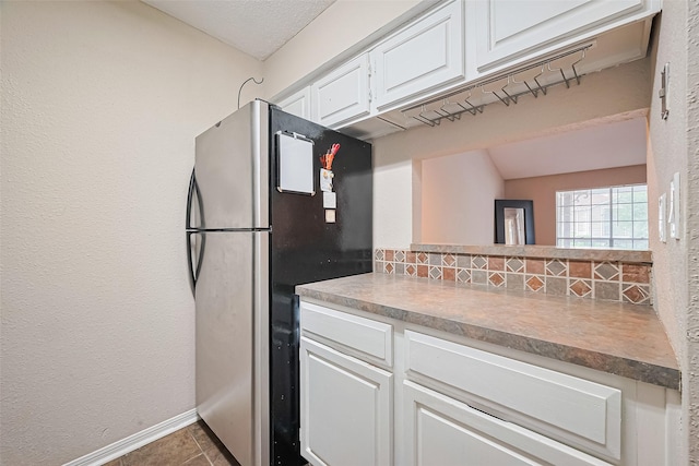 1860 White Oak Dr Unit 334, Houston, TX 77009 - kitchen with freestanding refrigerator, white cabinetry, tasteful backsplash, and dark tile patterned floors
