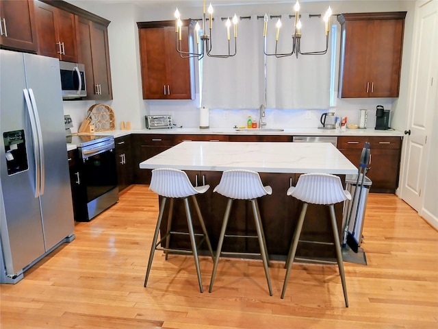 3333 Kilgore St, Houston, TX 77021 - kitchen featuring stainless steel appliances, a chandelier, light wood-type flooring, and a breakfast bar