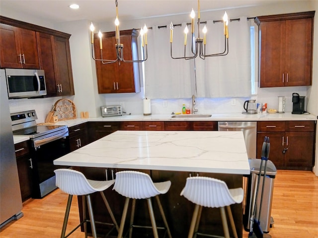 3333 Kilgore St, Houston, TX 77021 - kitchen featuring appliances with stainless steel finishes, a breakfast bar, light wood-type flooring, light stone counters, and recessed lighting