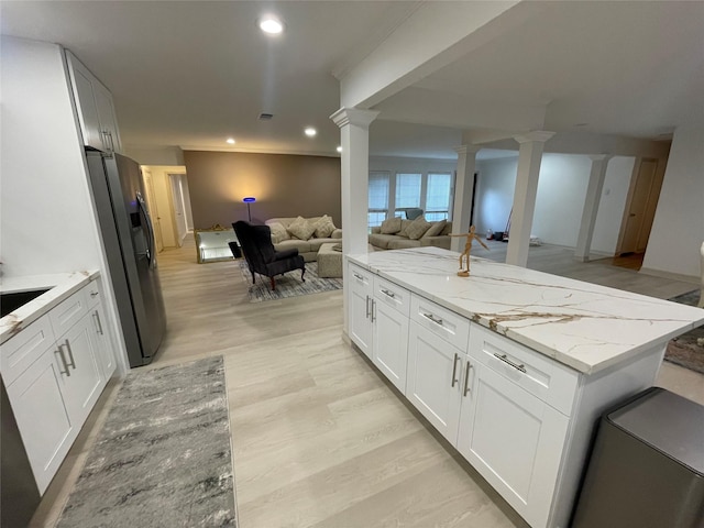 12834 Tosca Ln, Houston, TX 77024 - kitchen with stainless steel fridge, ornate columns, open floor plan, light stone counters, and recessed lighting