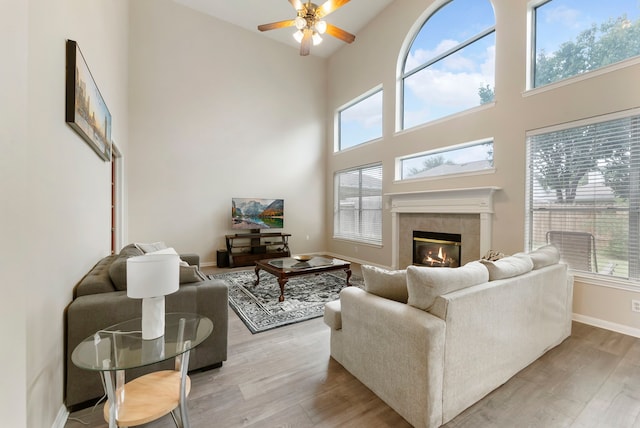 3202 Stoneydale Ln, Spring, TX 77388 - living room featuring light wood finished floors, a ceiling fan, a tiled fireplace, plenty of natural light, and a high ceiling