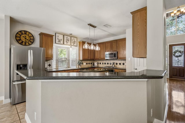 16407 Bogan Flats Ct, Houston, TX 77095 - kitchen featuring appliances with stainless steel finishes, brown cabinetry, decorative backsplash, pendant lighting, and light tile patterned flooring
