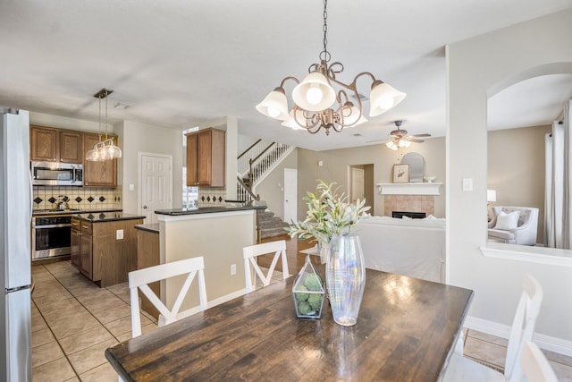 16407 Bogan Flats Ct, Houston, TX 77095 - dining space featuring arched walkways, a ceiling fan, a tile fireplace, and light tile patterned floors
