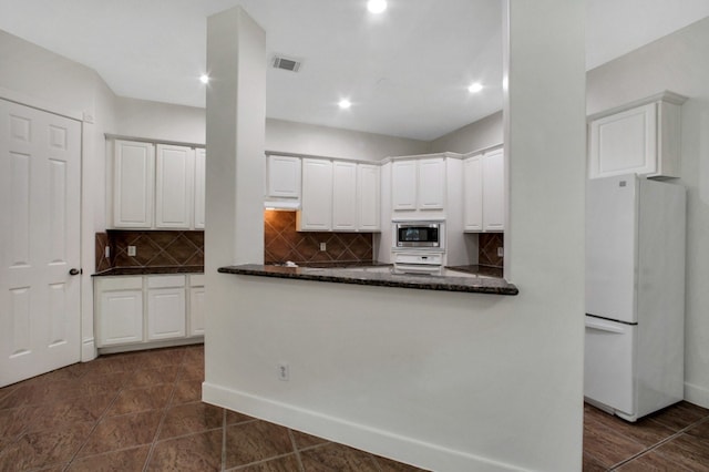 4734 Cashel Glen Dr, Houston, TX 77069 - kitchen featuring freestanding refrigerator, stainless steel microwave, tasteful backsplash, white cabinets, and dark stone countertops