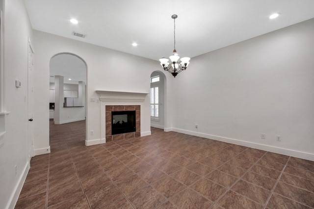 4734 Cashel Glen Dr, Houston, TX 77069 - unfurnished living room with recessed lighting, a chandelier, arched walkways, a tiled fireplace, and dark tile patterned floors