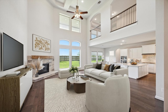 27403 Laurel Bay Ct, Katy, TX 77494 - living room featuring dark wood-style floors, a fireplace, a towering ceiling, ceiling fan, and recessed lighting
