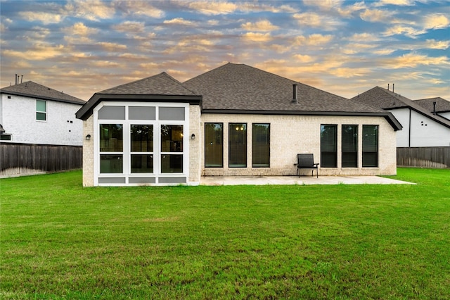 14811 Opossum Branch Ct, Cypress, TX 77433 - back of property at dusk with a patio, a fenced backyard, a shingled roof, and brick siding