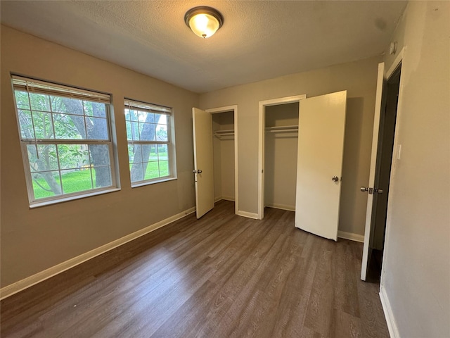 2222 8th St, Houston, TX 77547 - unfurnished bedroom featuring multiple closets, dark wood-style floors, and a textured ceiling
