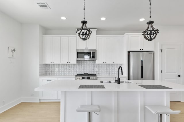 104 E 44th St Unit A, Houston, TX 77018 - kitchen with appliances with stainless steel finishes, light countertops, light wood-style floors, a breakfast bar, and recessed lighting